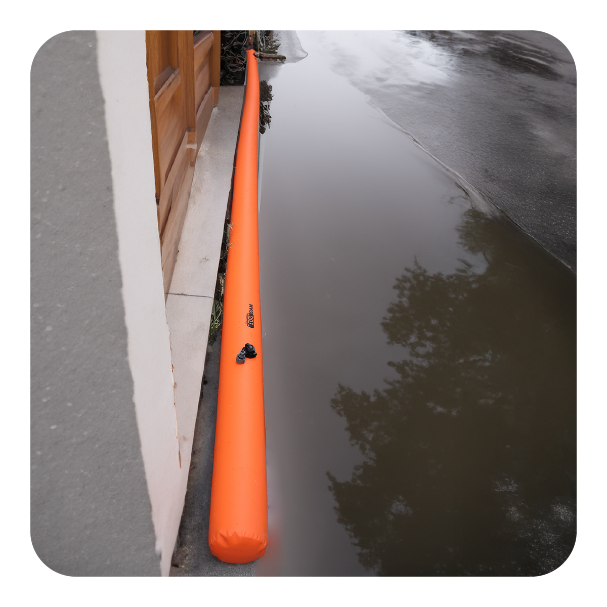 Orange Log Dam water-filled barrier on a wet pavement next to a building