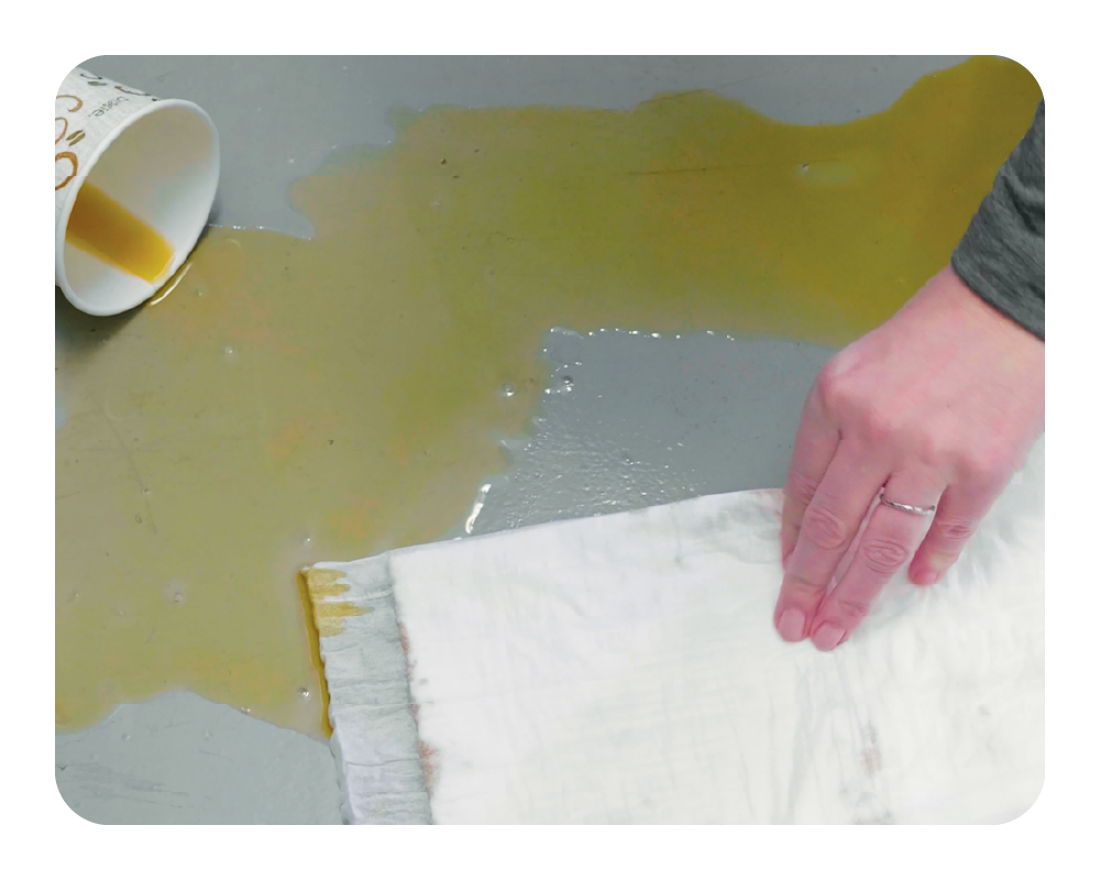 Hand cleaning up a coffee spill with a Quick Dam Mat
