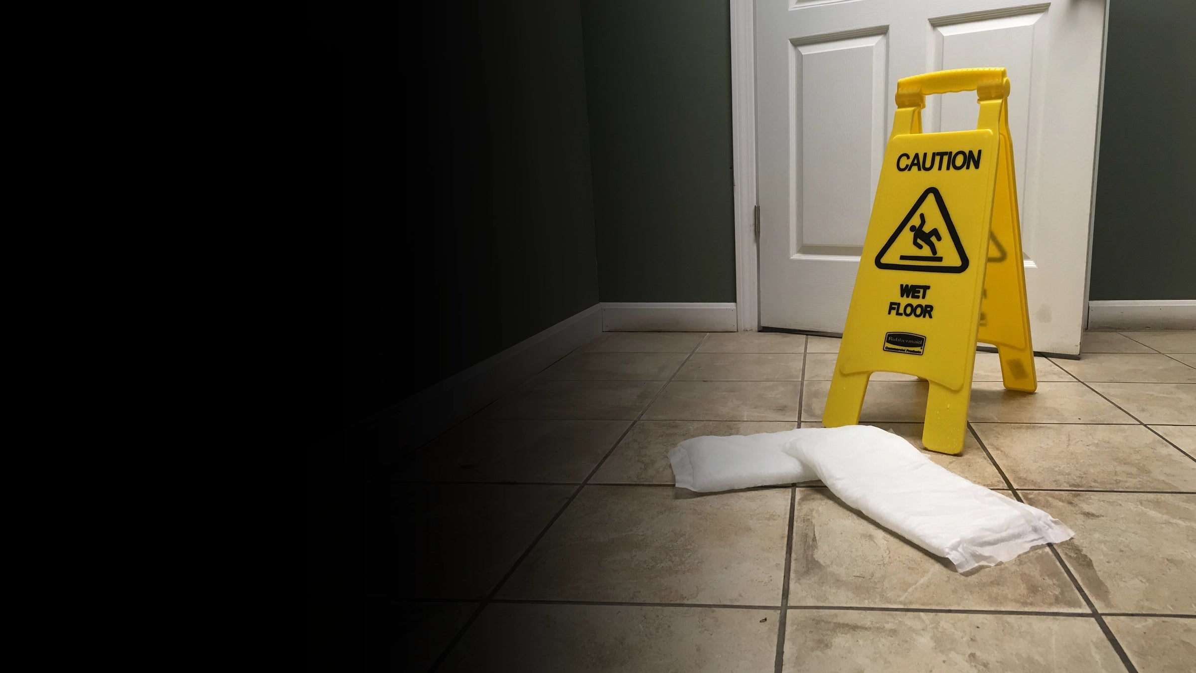 Yellow caution sign for wet floor on a tiled floor with white Quick Dam Mats