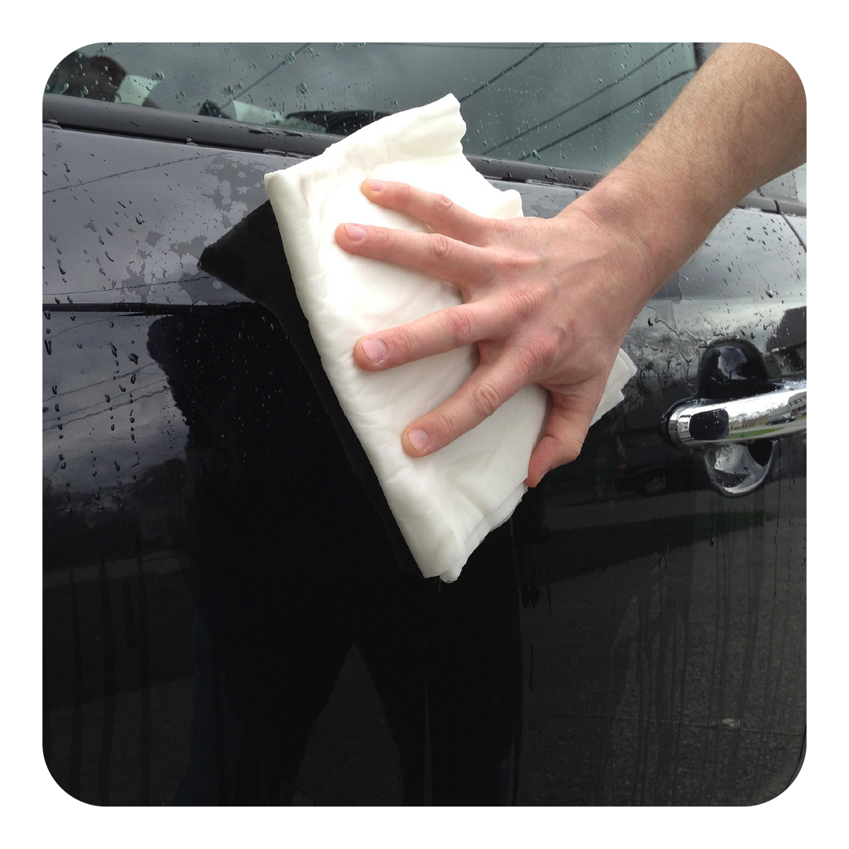 Person cleaning a car window with a white Quick Dam Mighty Mat