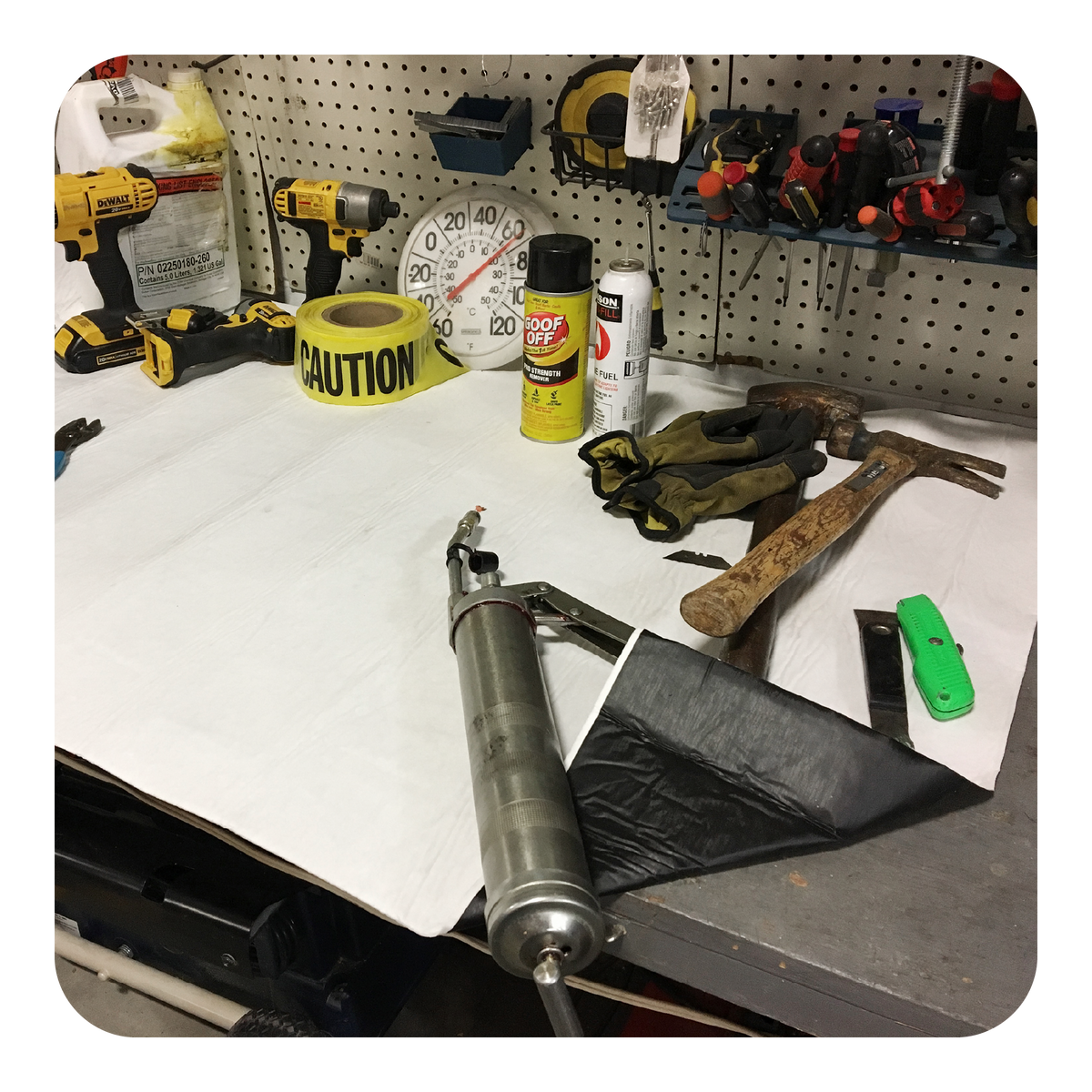 Workbench with tools and equipment including a shock absorber, hammer, and spray cans.