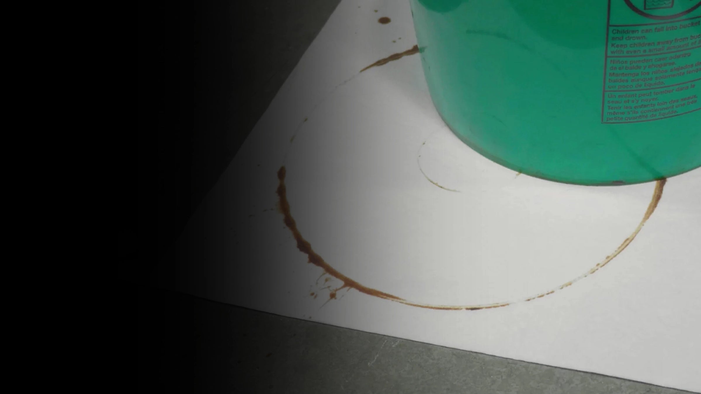 Green container with a brown stain on a white mighty mat