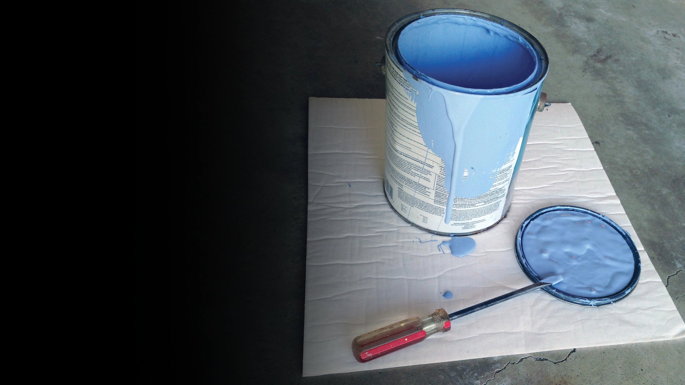 Blue paint can with a brush and screwdriver on a quick dam mighty mat