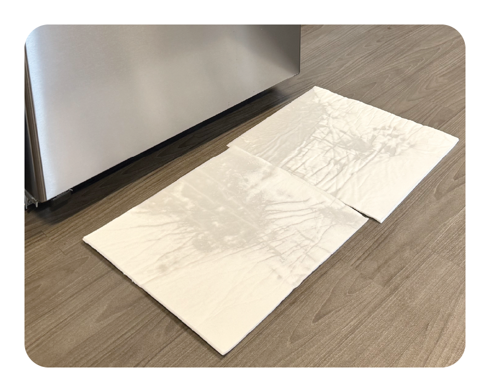 Stainless steel fridge with white mighty mats on wood floor