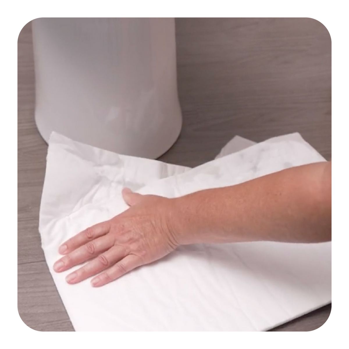 Person wiping around toilet with white mighty mat on a wooden surface