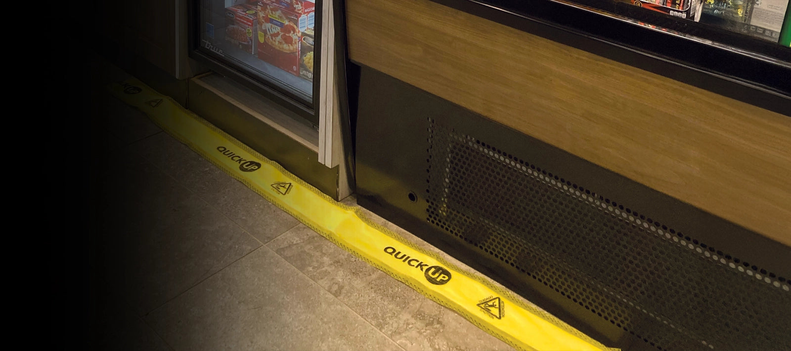 Yellow safety Quick Up Dam on a floor in grocery fridge aisle