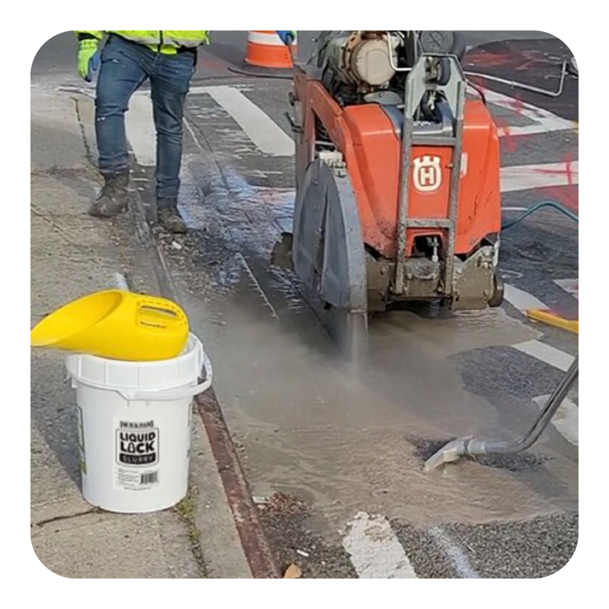 Person operating a road milling machine with a bucket labeled 'Quick Dam Liquid Lock' nearby.