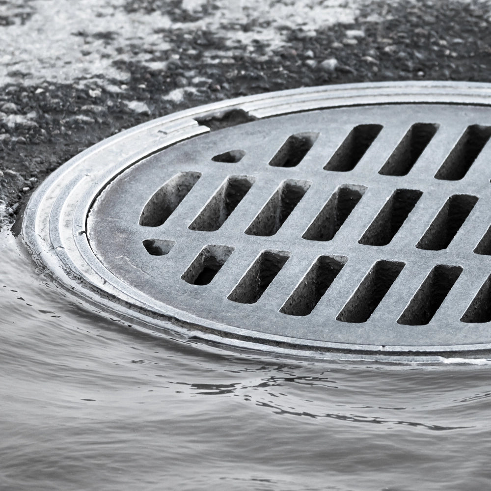 Metal manhole cover on a street with water flowing around it