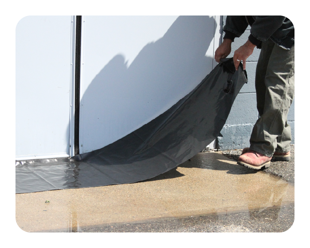 Person unrolling black water curb in front of a white double door