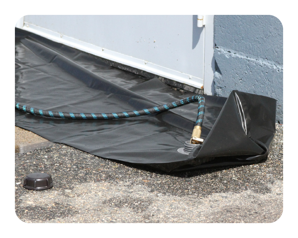 Black water curb being filled with a garden hose on a concrete background