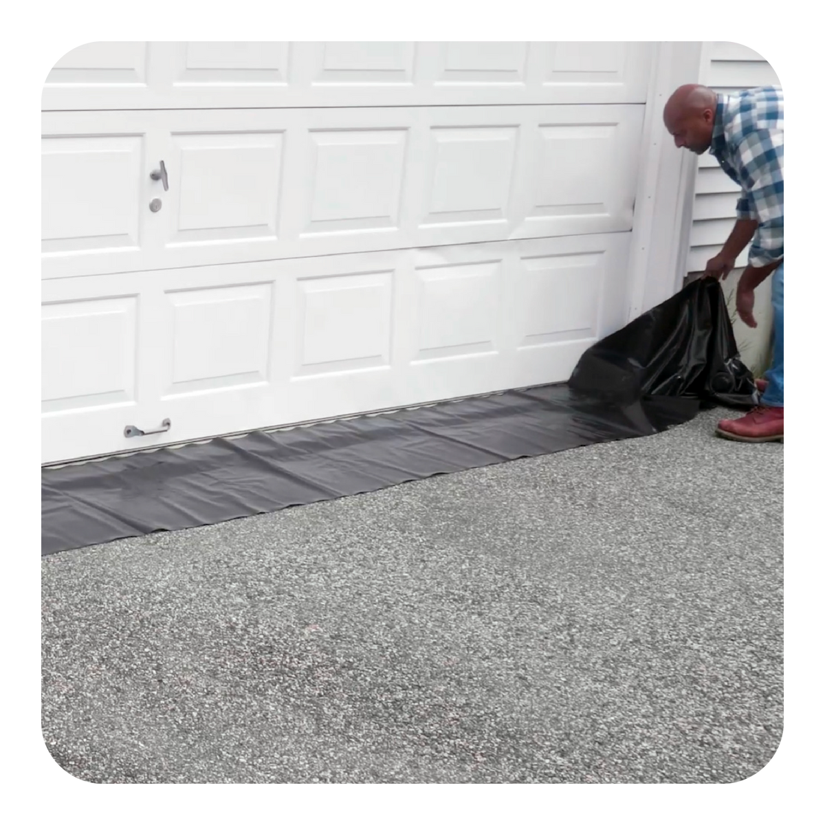 Person using a black Water Curb to protect a garage from flood water
