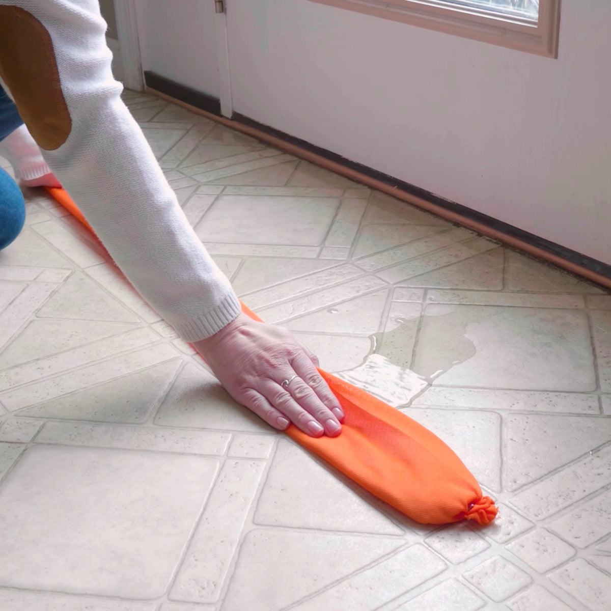 Person using an orange water dam on a tiled floor