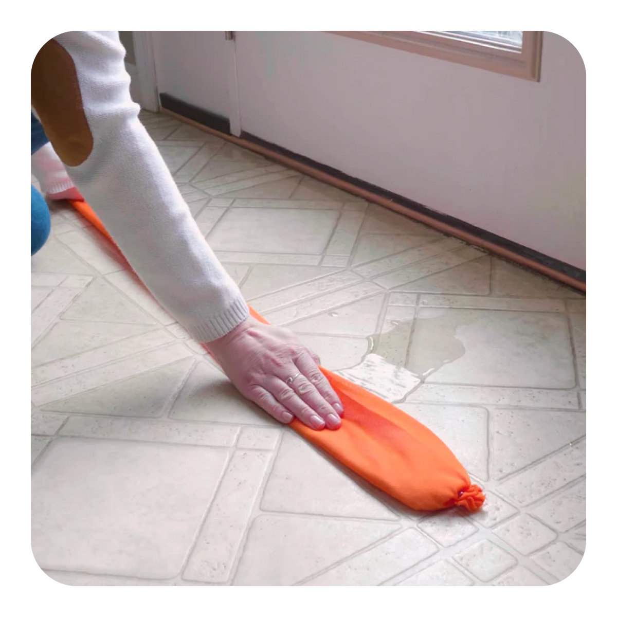 Woman using a Quick Dam water dam to absorb water under a doorway