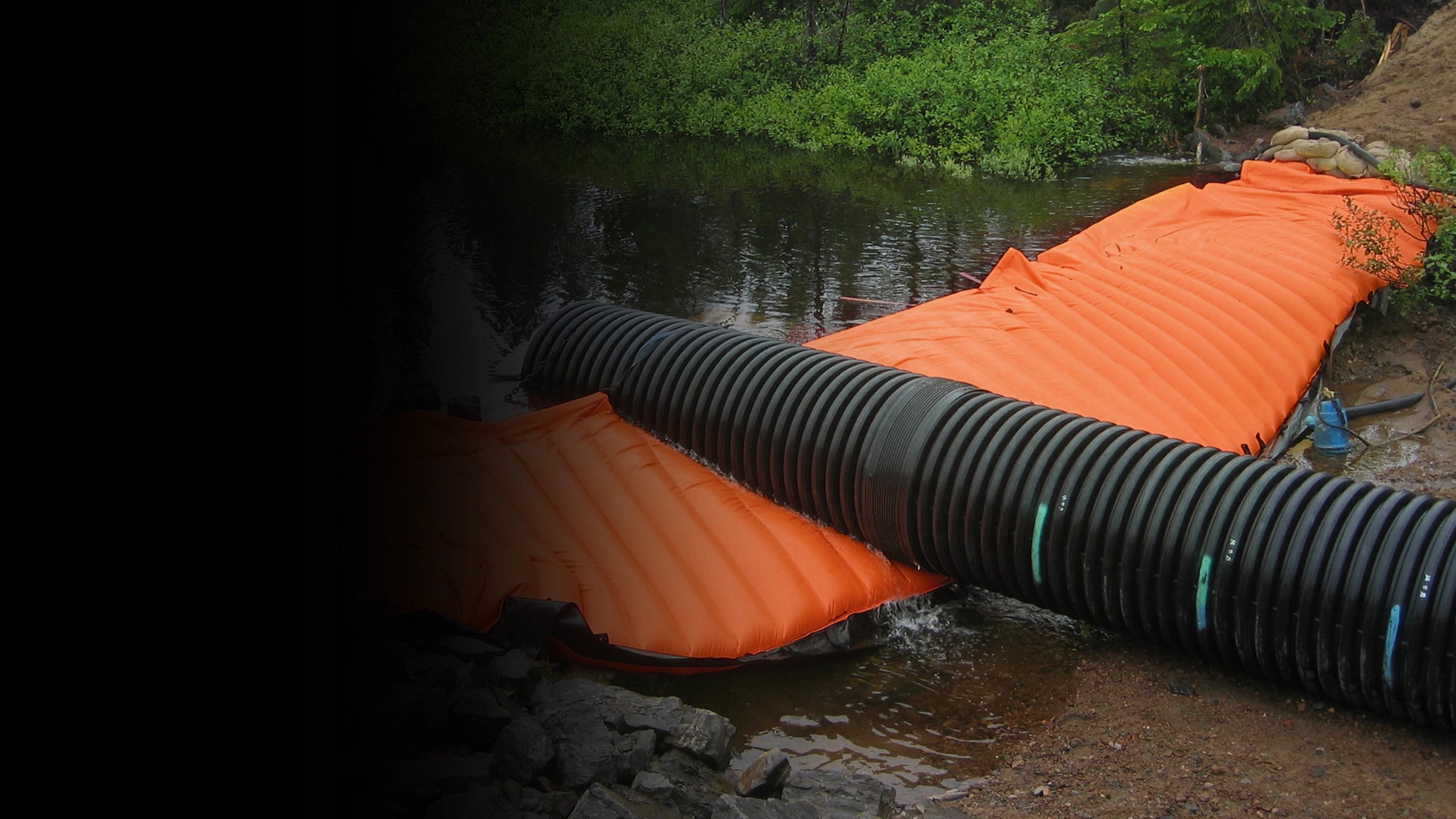 Orange water force with black pipe on a rocky surface near water