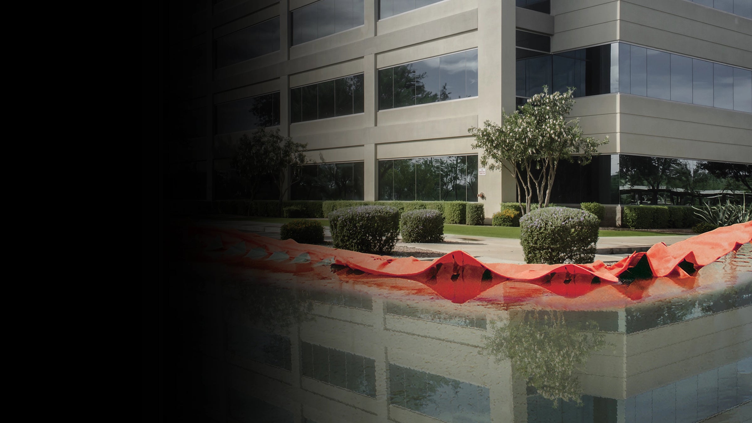 Orange water force in front of a modern office building holding back flood water