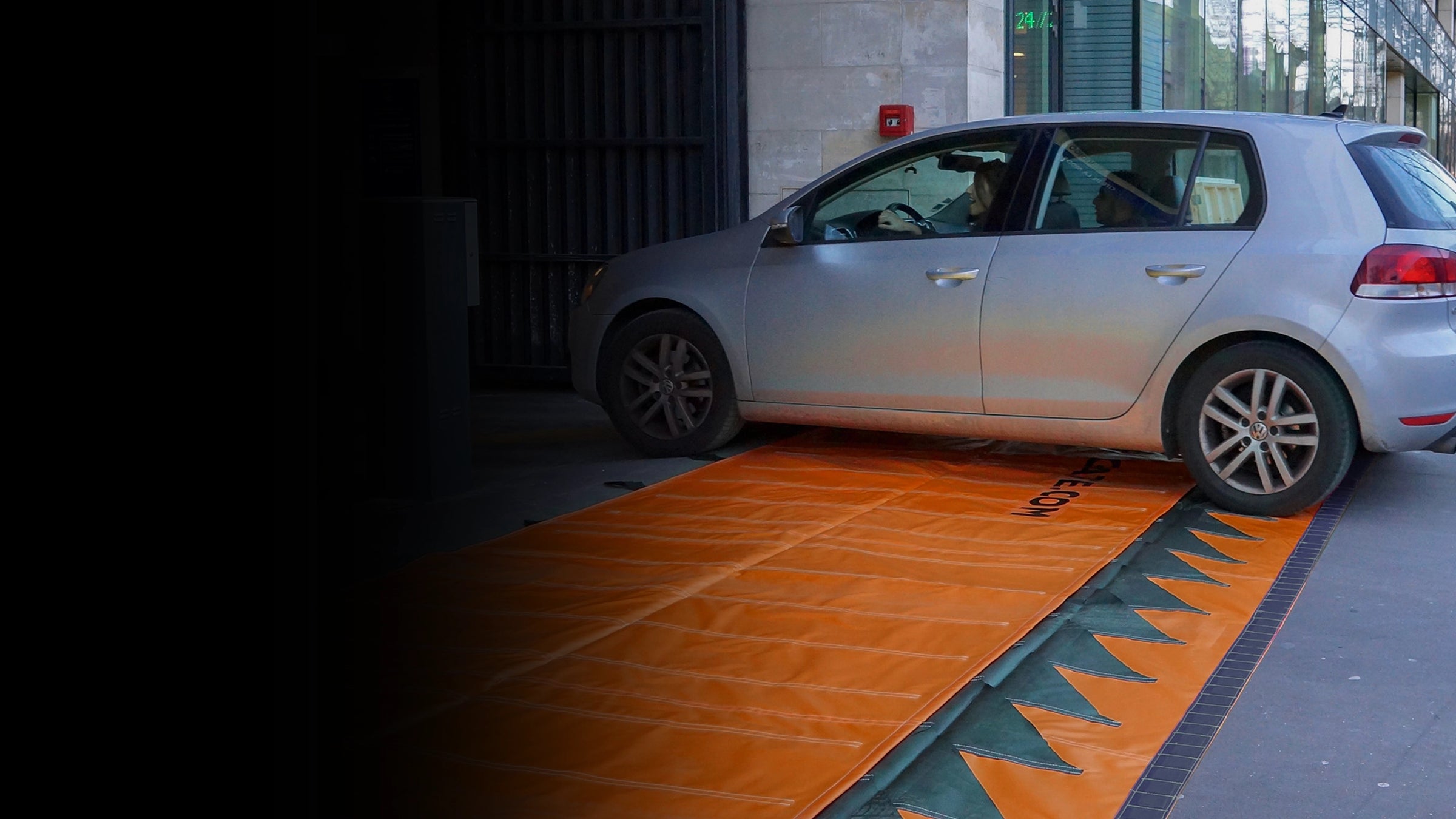 Car entering a parking garage driving over an orange water force